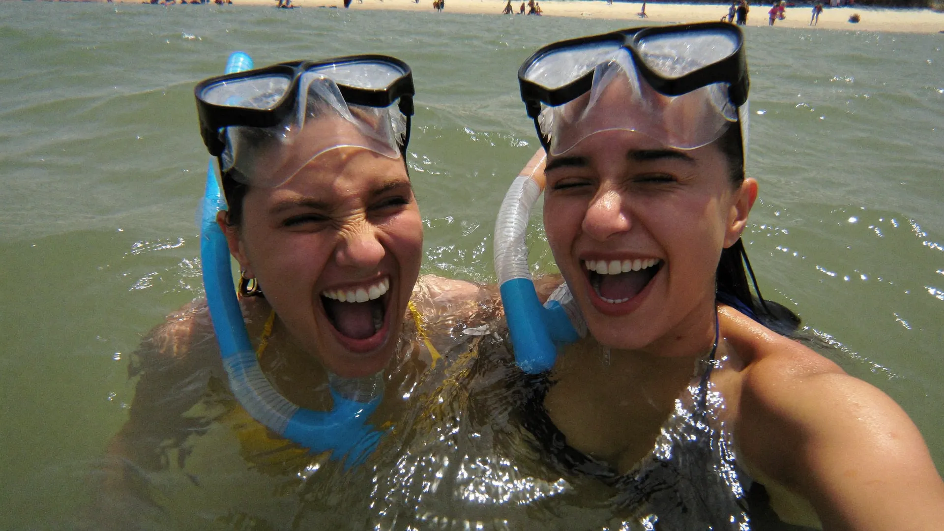 Dos visitantes con visores de snorkel riendo en el mar de Akumal