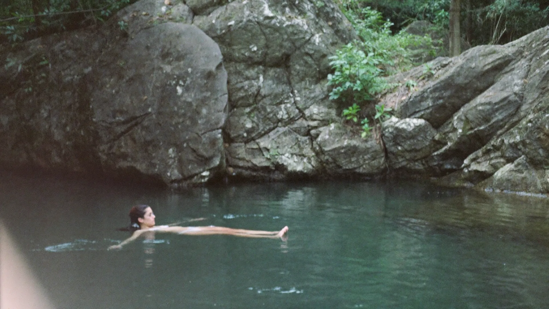 Persona flotando en el agua tranquila de una caleta rodeada de selva cerca de Tulum